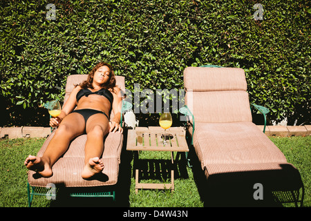 Donna in bikini a prendere il sole nel prato sedia Foto Stock