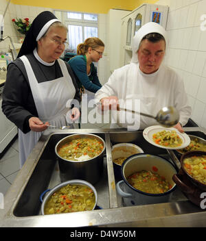 Le persone nel bisogno di ricevere un pasto caldo e dessert dalla sorella Celina a 'Elisabeth tabella dell' ('Elisabeth-Tisch') all'ospedale Santa Elisabetta e Santa Barbara a Halle, Germania, 15 dicembre 2009. Più di 60 destinatari del tedesco di disoccupazione Hartz IV, senzatetto e di altre persone in stato di bisogno può avere il pranzo per un euro all'ospedale del cibo banca. Circa 1 milioni di euro Foto Stock