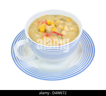 A che serve di mais, di patata e pepe rosso chowder in una strisce blu cup sul piattino. Foto Stock