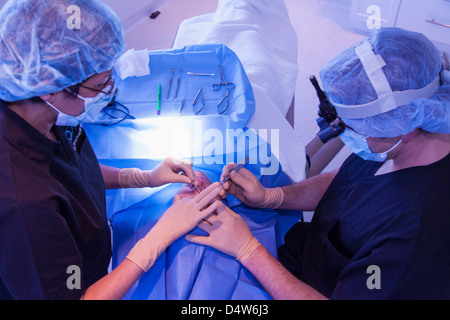 I chirurghi con il paziente in sala operatoria Foto Stock