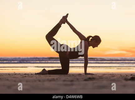 La donna a praticare yoga sulla spiaggia Foto Stock