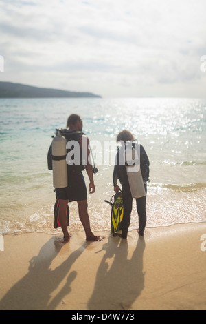 Subacquei camminando sulla spiaggia tropicale Foto Stock