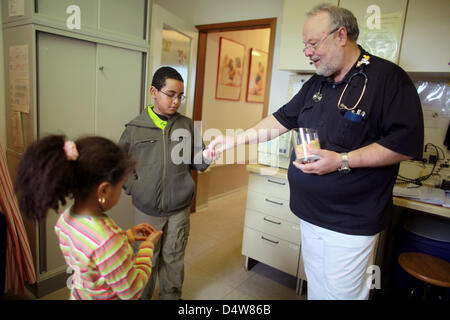 (File) - Un file di dpa foto datata 27 marzo 2009 mostra un pediatra distribuendo caramelle per due bambini della sua pratica a Colonia, in Germania. Foto: Rolf Vennenbernd Foto Stock