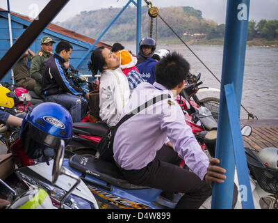 Marzo 11, 2013 - Luang Prabang, Luang Prabang, Laos - Una donna equilibra il suo bambino sulla sua motocicletta mentre lei lo cavalca un traghetto per attraversare il fiume Mekong vicino a Luang Prabang. Il fiume Mekong traghetti stanno scomparendo come ponti attraverso il fiume sono completati e strade lungo il fiume sono lastricate. La pavimentazione di autostrada a 13 da Vientiane per vicino alla frontiera cinese ha cambiato il modo di vita nelle zone rurali del Laos. Gli abitanti di un villaggio vicino a Luang Prabang hanno utilizzato per prendere le barche inaffidabili che ha avuto tre ore di viaggio di andata e ritorno per ottenere dal case per il centro turistico di Luang Prabang, ora essi prendere 40 minuti di viaggio di andata e ritorno in autobus Foto Stock