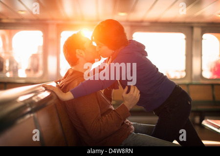 Giovane kissing sul traghetto al tramonto Foto Stock