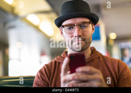 L'uomo tramite telefono cellulare sul banco di lavoro Foto Stock