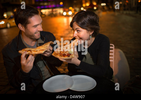 Paio mangiare la pizza sulla strada di città Foto Stock