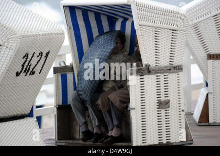 Una donna stessa protegge dalla pioggia con un ombrello come si siede in una sedia spiaggia sul Mar Baltico isola di Sylt, Germania, 16 settembre 2010. Foto: Bernd Wuestneck Foto Stock