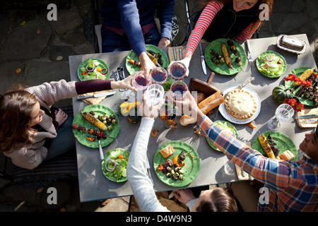 Amici tostare ogni altro a tavola Foto Stock