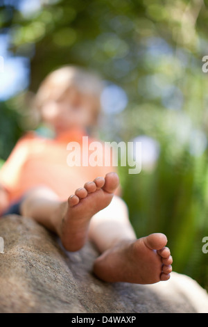 Chiusura del ragazzo in piedi sulla roccia Foto Stock