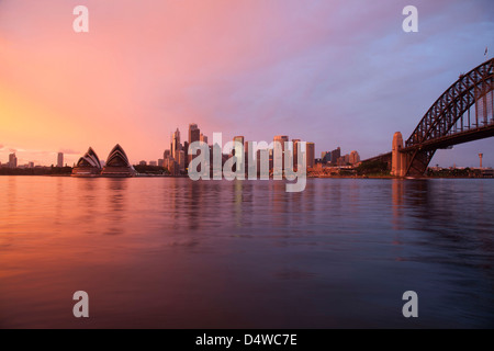 Sunrise incandescente al di sopra della Sydney Opera House e lo skyline del CBD Sydney New South Wales AUSTRALIA Foto Stock