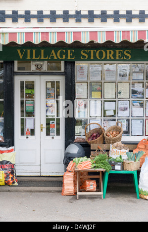 La Moulton village memorizza un tradizionali magazzini generali e ufficio postale in Suffolk REGNO UNITO con il negoziante in piedi al di fuori. Foto Stock