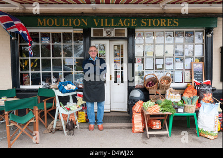 La Moulton village memorizza un tradizionali magazzini generali e ufficio postale in Suffolk REGNO UNITO con il negoziante in piedi al di fuori. Foto Stock