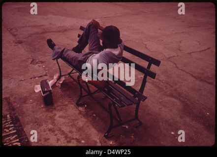 L'uomo sdraiati su una panchina nel parco con la sua Radio sul Parco Reis Boardwalk in New York City ... 07/1974 Foto Stock