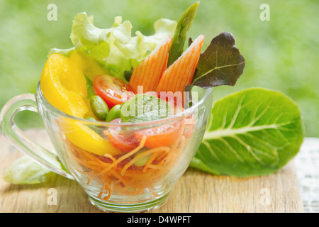 Verdura fresca insalata in vaschetta trasparente sul verde della natura Foto Stock
