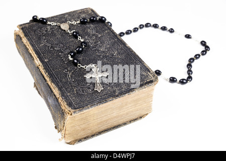 I grani del rosario e croce giacente su una pagina aperta della bibbia isolato su uno sfondo bianco. Foto Stock