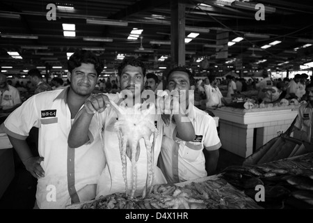 Un gruppo di uomini al mercato del pesce tenendo alto il polpo, Dubai, Emirati Arabi Uniti Foto Stock