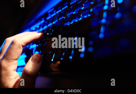 Mano d'uomo digitando su una tastiera di colore blu. Foto Stock