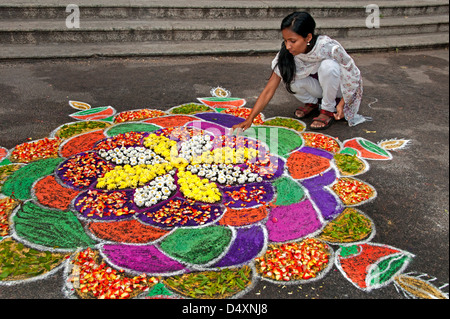 Chennai donna sta compiendo un Rangoli design con fiori in un Indiano street durante il festival indù di Sankranthi India India Foto Stock