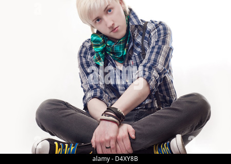 L'elegante giovane ragazzo si siede su uno sfondo bianco Foto Stock