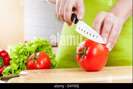 Donna con le mani in mano il taglio di pomodoro fresco su cucina Foto Stock