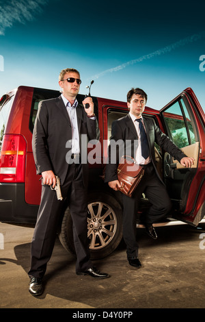 La guardia del corpo e il suo boss lasciare l' auto Foto Stock