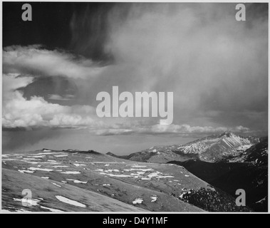 Una fotografia in bianco e nero delle vette del Rocky Mountain National Park, Colorado, scattata dal famoso fotografo Ansel Adams. L'immagine mostra nuvole sospese, un orizzonte suggestivo e paesaggi aspri, conservati dagli Archivi nazionali e dal National Park Service degli Stati Uniti. Foto Stock