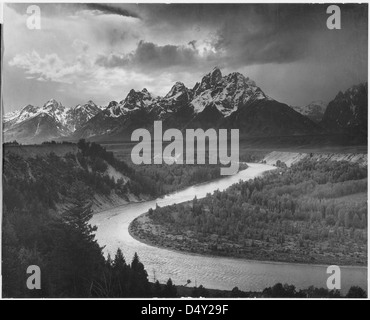 Questa fotografia di Ansel Adams cattura il Grand Tetons e il fiume Snake nel Grand Teton National Park, Wyoming. L'immagine in bianco e nero mostra l'iconica catena montuosa con il fiume che scorre in primo piano, sottolineando la bellezza naturale del parco. Questa foto, scattata dal famoso fotografo, mette in evidenza il suggestivo paesaggio del West americano. Foto Stock