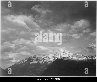 Una fotografia in bianco e nero di Ansel Adams di Heaven's Peak nel Glacier National Park, Montana, scattata come parte del percorso panoramico "Going-to-the-Sun". L'immagine cattura il paesaggio spettacolare con nuvole scure e montagne evidenziate. Foto Stock