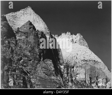 Una fotografia in bianco e nero di una formazione rocciosa nello Zion National Park, Utah, scattata nel 1941 da Ansel Adams. L'immagine cattura la dura bellezza del paesaggio desertico, con torreggianti formazioni rocciose contro un cielo scuro. Foto Stock