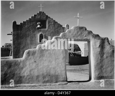Una fotografia del 1941 di Ansel Adams che mostra il cancello d'ingresso alla Chiesa di Taos Pueblo, un monumento storico nazionale nel nuovo Messico. L'immagine cattura le caratteristiche architettoniche della chiesa in bianco e nero. Foto Stock