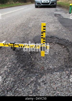 Buche, guasti meccanici, strumento di misura dei difetti, indagine, automobilisti, negligenza, danni, veicoli, lesioni personali, dovere di mantenere la strada. Foto Stock