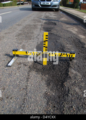 Buche, guasti meccanici, strumento di misura dei difetti, indagine, automobilisti, negligenza, danni, veicoli, lesioni personali, dovere di mantenere la strada. Foto Stock