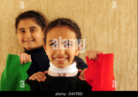 Il Kuwait Kuwait City, di 2 ragazze sorridenti mascherate con bandiera kuwaitiana. (MR) Foto Stock