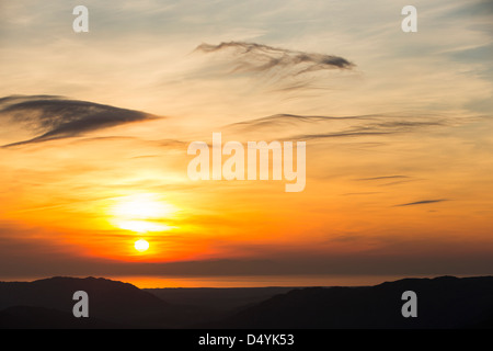 Il sole tramontare sull'Isola di Man visto da Hardknott Pass, guardando verso il basso Eskdale nel distretto del lago, UK. Foto Stock