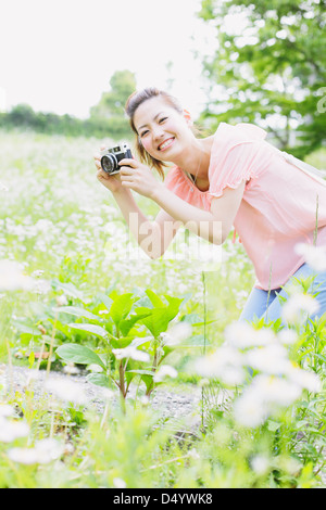 Donna Giapponese a scattare foto in un prato Foto Stock