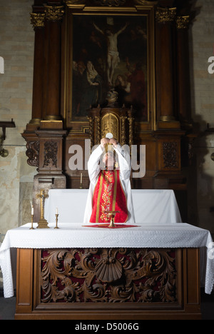 Momento di consacrazione da parte di un sacerdote di una chiesa medioevale con il XVII secolo interni antichi (compresa la verniciatura) Foto Stock