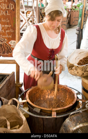 Una cameriera giovane che indossa un abito medievale come un monaco Gourmet, impegnato a mescolare un mix di mandorle candite adesive Tallinn, un dolce tradizionale, sulla sua ca gommata Foto Stock