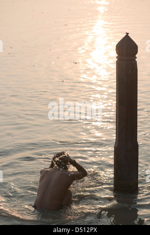 Un indù devoto bagna nel sacro Yamuna rive di sunrise a Vishram Ghat, Mathura, Uttar Pradesh, India Foto Stock