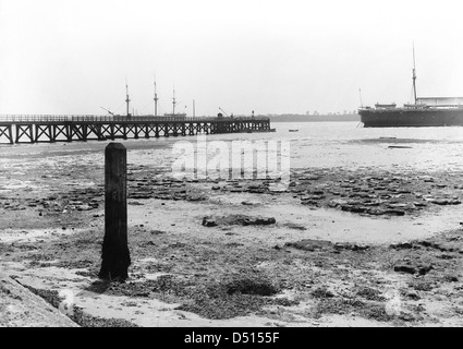 Questa fotografia cattura una vista dalla riva verso il molo di Shotley durante la bassa marea, offrendo una rappresentazione pacifica del paesaggio e delle infrastrutture marittime. Foto Stock