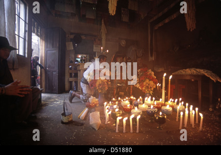 La gente del posto pay rispetti a maximon presso un santuario a lume di candela in Santiago Atitlan Foto Stock