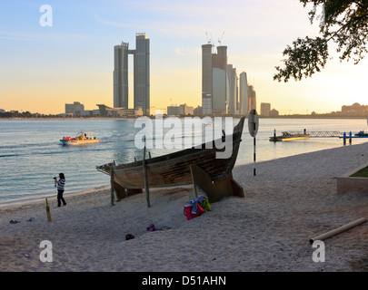 Sambuco tradizionale sulla spiaggia, alti edifici moderni in background, Abu Dhabi Heritage Village, Emirati Arabi Uniti Foto Stock