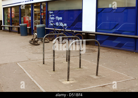 Vuoto parcheggio bici rastrelliere di fronte al supermercato Tesco Express in Cheddar con bici accatastate presso lo sportello anteriore Foto Stock