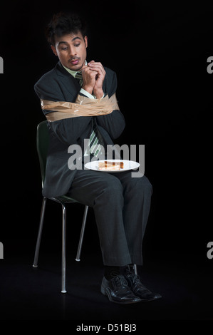 Imprenditore legato con nastro adesivo e cercando di toast su una piastra Foto Stock