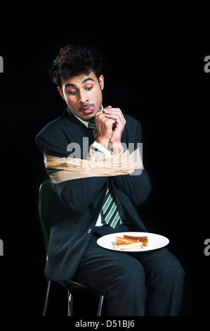 Imprenditore legato con nastro adesivo e cercando di toast con avidità Foto Stock