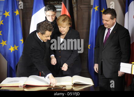 Bundeskanzlerin Angela Merkel (CDU, M.) und der franzoesische Staatspraesident Nicolas Sarkozy (l) tragen sich am Freitag (10.12.10) im Rathaus in Freiburg im Rahmen des Ministerrats Deutsch-Franzoesischen beobachtet vom Freiburger Buergermeister Dieter Salomon (Gruene, hinten) und dem Baden-Wuerttembergs Ministerprasidenten, Stefan Mappus (CDU, r.), in das Goldene Buch der Stadt Foto Stock