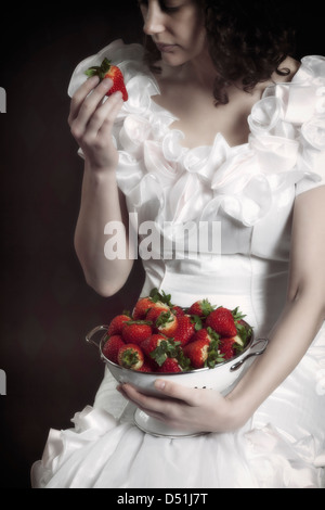 Una ragazza in un abito bianco con un colapasta pieno di fragole Foto Stock