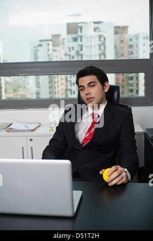 Imprenditore tenendo una palla che guardano un notebook Foto Stock