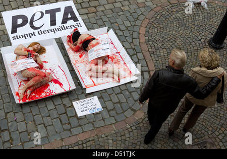 Metà nacked e cosparso di sangue teatrale, attivisti per i diritti degli animali dell'animale organizzazione di destra Peta Germania giacciono sul materiale di confezionamento e ricoperto di cellophane nella zona pedonale a Osnabrück, Germania, 29 settembre 2010. Peta ha iniziato una petizione al più alto è il tasso fiscale del sette per cento per i prodotti a base di carne al fine di fermare la sofferenza e uccisione di come essi estim Foto Stock