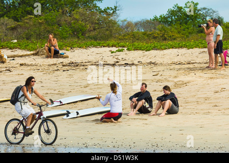 Lezione di Surf in corso & ciclista sulla Playa Guiones surf beach, Nosara, Nicoya peninsula, provincia di Guanacaste, Costa Rica Foto Stock